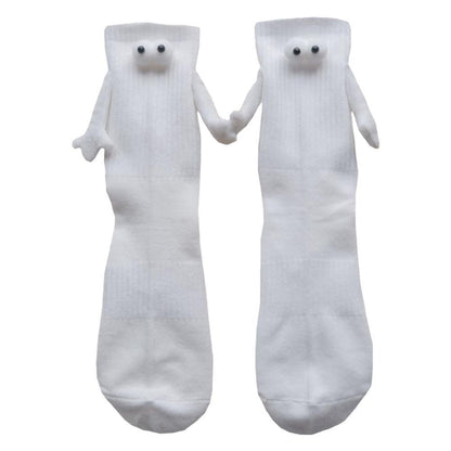 A pair of 3D eye socks with magnetic hands at the end of little arms are holding hands. The background is white. 