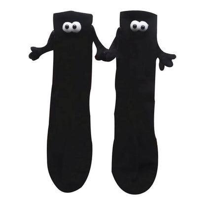 Black magnetic attraction socks with 3D eyes and little arms and hands. They are holding hands.