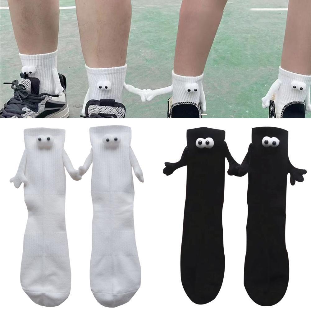 A couple wearing magnetic attraction socks. The socks have 3D eyes and little arms. The socks are holding hands.