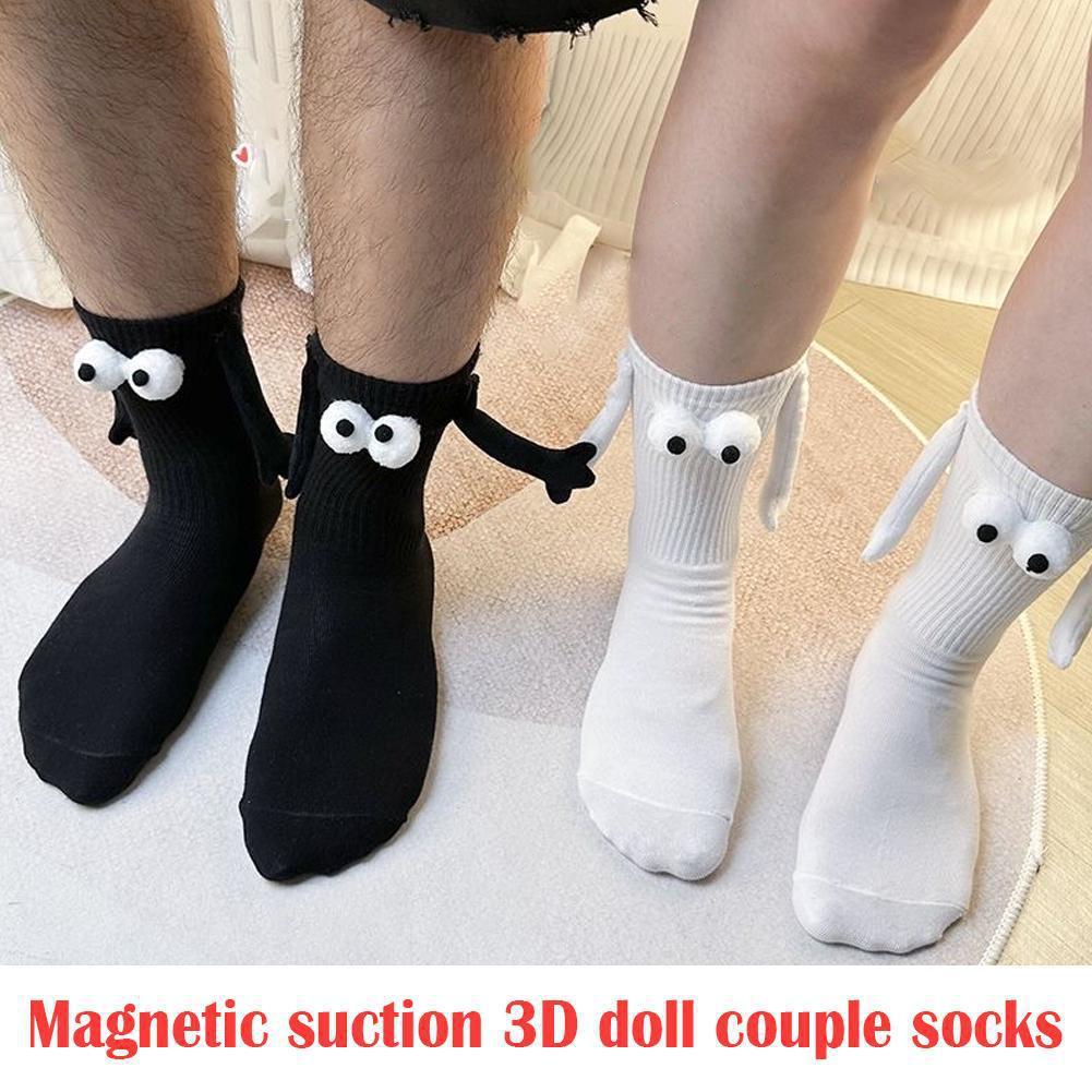 A male and female standing next to each other are both wearing 3D magnetic attraction socks. The male is wearing black and the female is wearing white. The socks are holding hands. There are words on the picture they say- Magnetic suction 3D doll couple socks. There is no suction. They are magnets. 